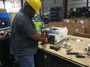 A RecycleForce employee takes apart a television to separate the parts for recycling.